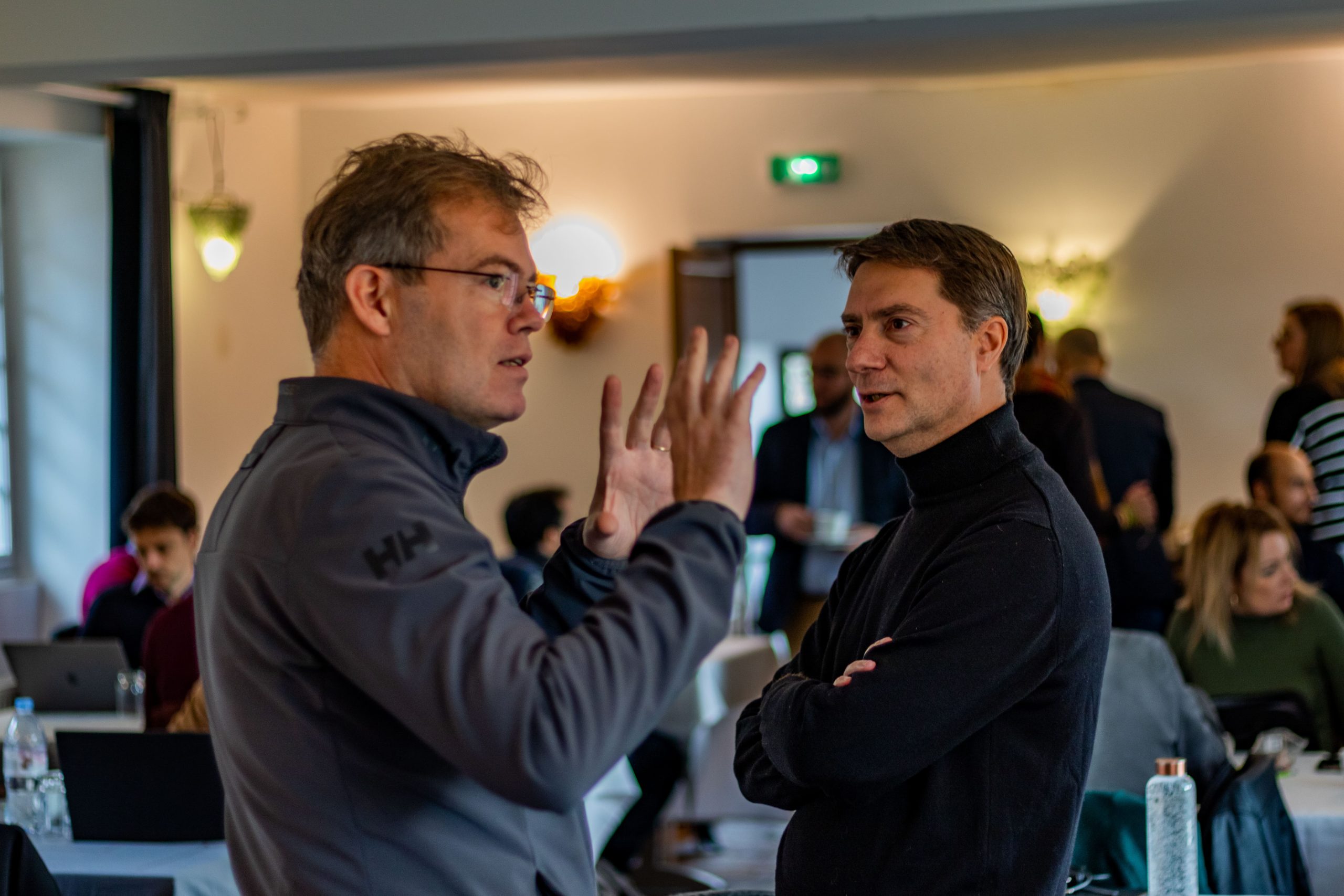 Deux hommes discutant lors d'un événement professionnel, illustrant l'acquisition de Global Map Solution par Geoptis, Groupe La Poste.