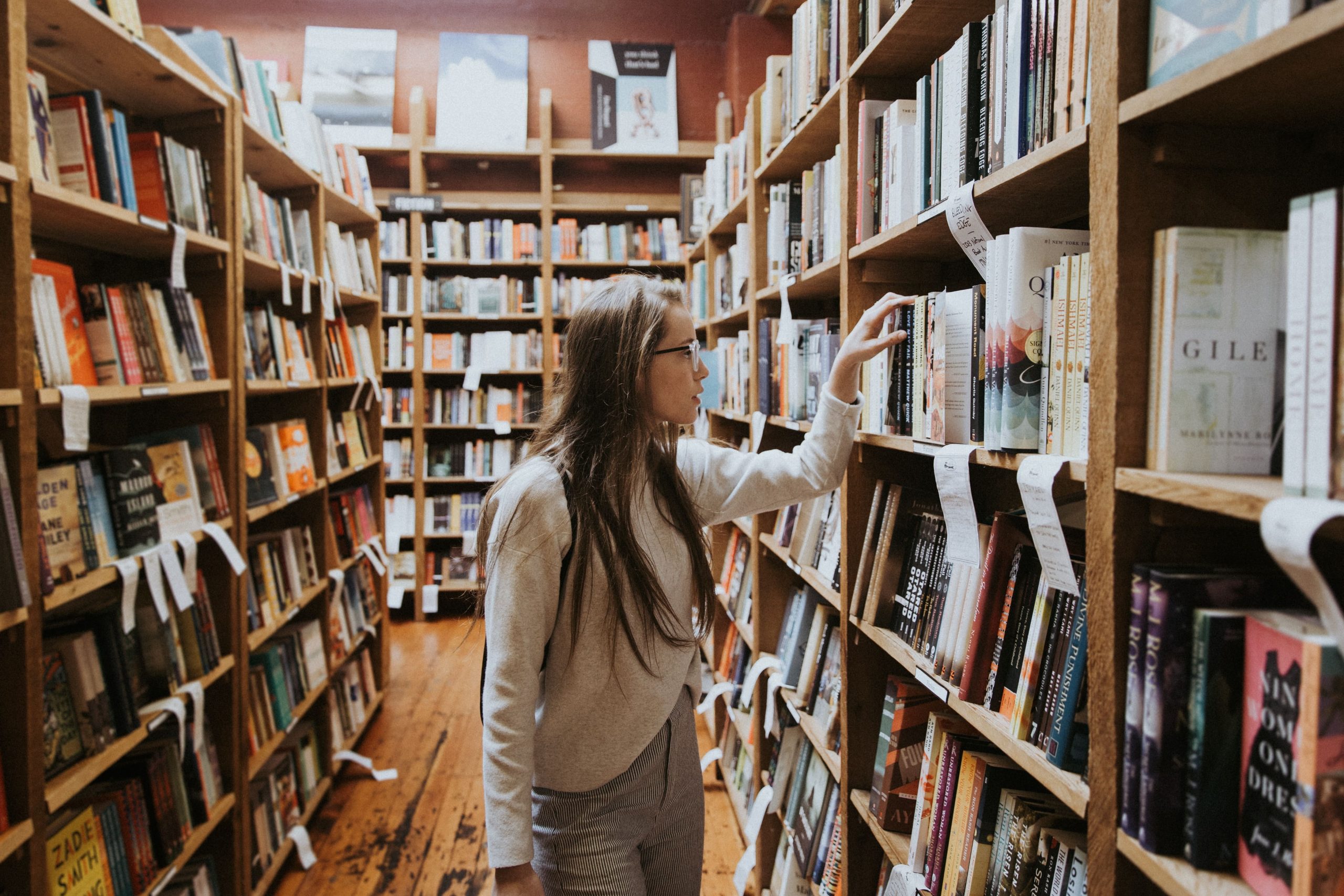 Une femme cherchant un livre dans une bibliothèque, illustrant le lien entre le niveau d'éducation et l'emploi.